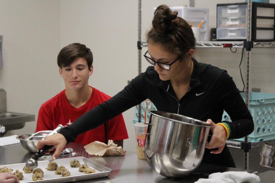 Seniors Carlyn Briganti and Samuel Strong scoop out balls of cookie dough during the cookie contest.
