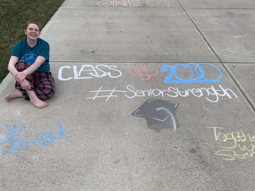 Senior Cailyn Sykora sits next to her drawings. Besides the 2020 seniors drawing, I did a full Disney themed square with a bunch of side-kick characters, Sykora (20) said. This was created to show support to her fellow classmates.