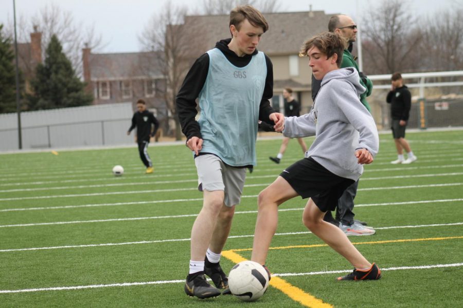 Joey Witt (22) is attempting to steal the ball from Joe Burns (22) during an after school soccer practice.