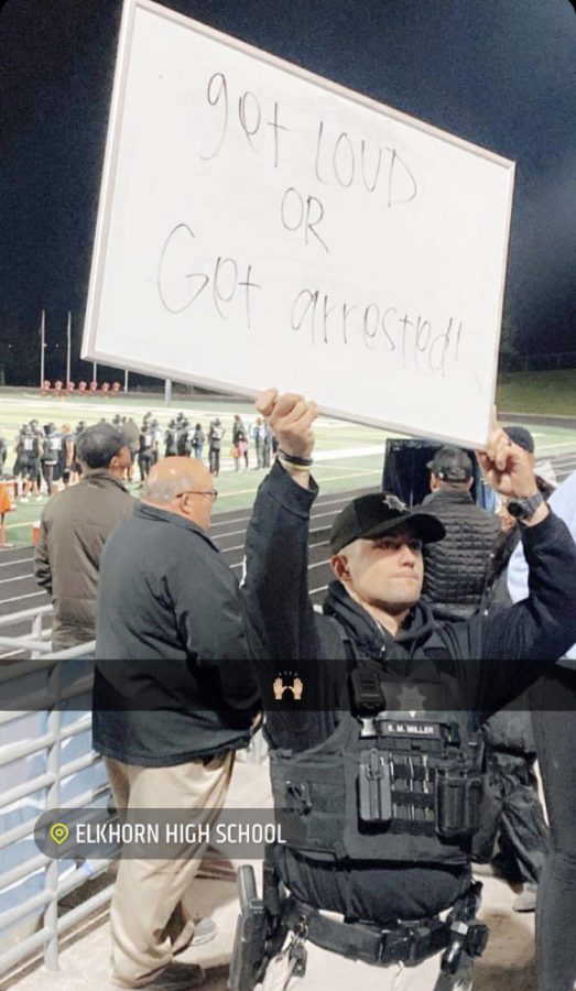 Get Loud: A school resource officer holds up a white board towards the student section at Elkhorn South High School. At a typical home football game, Mr. Mark Kalvoda Elk South principal said. We will have over 700 students in our high school student section. Elkhorn South High School has great participation during their football home games.