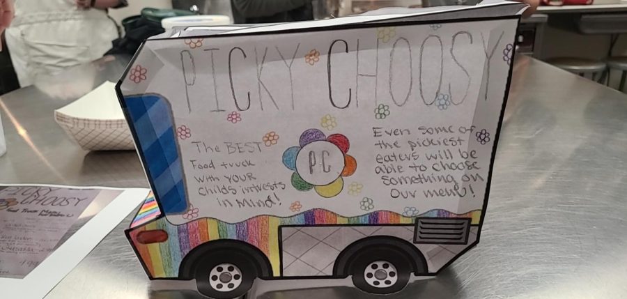 ARTS AND CRAFTS. A part of this project was to create a paper food truck to hold the paper “dollars” passed out by Ms. Schmit. “It’s a kids menu,” Sammy Otten (24) said. “That why I chose mac and cheese.”