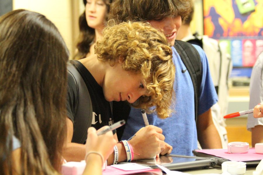 Freshman Kasen Brown writes his name on his laptop charger.  