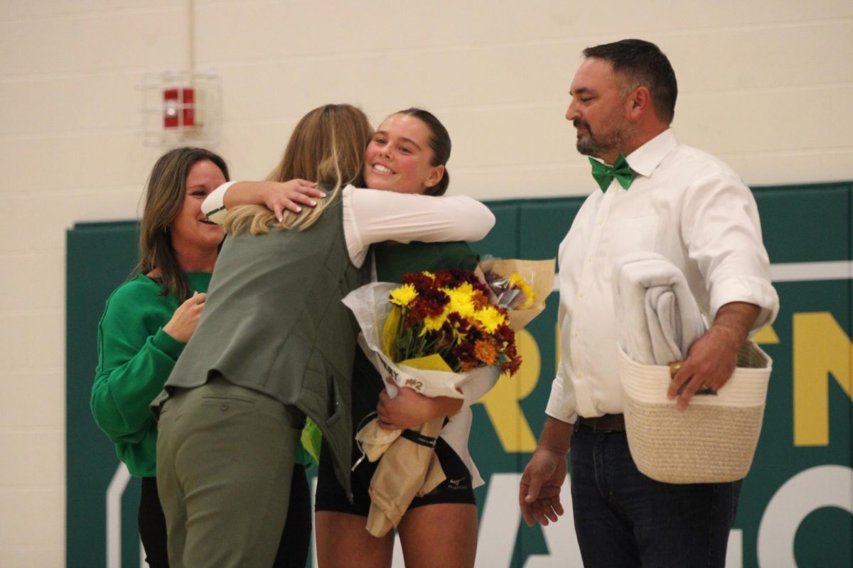 Avery Fotoplos (24) gives Head Coach Wendy Loberg a hug after receiving her flowers and gift for senior night.