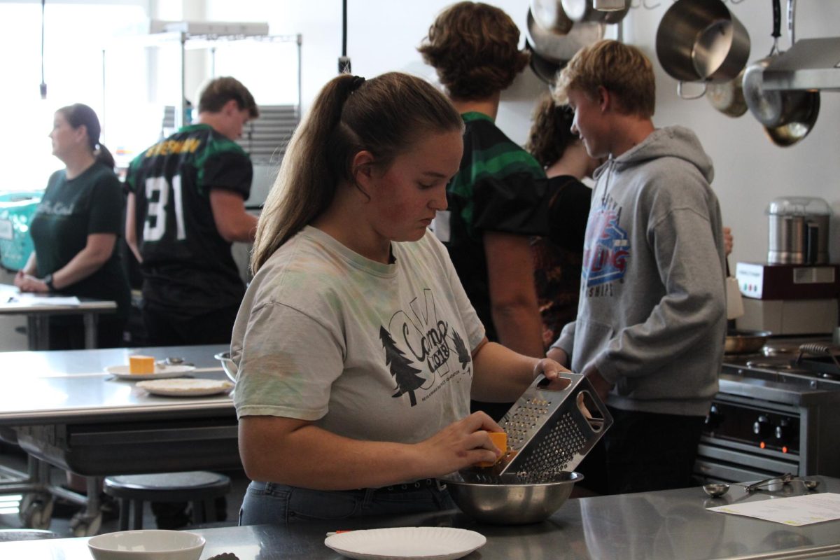 Senior Hermione Harris uses a box grater to shred a chunk of cheddar in Foods class. 