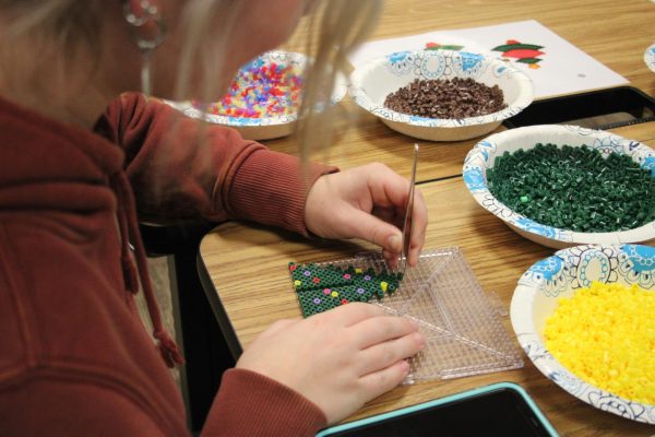 Claire Campbell, junior, works on a Perler bead Christmas tree design. The activity was hosted by the library. 