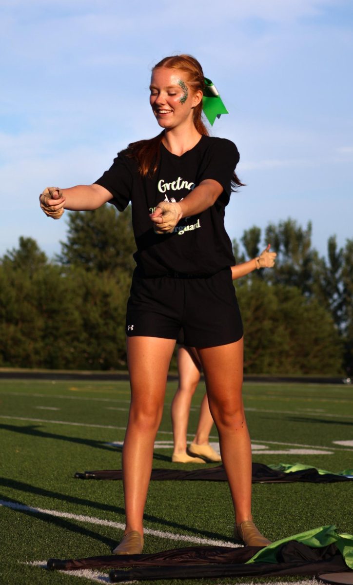 Mia Onwiler (26) smiles as she acts as a server from Italy during the GHS Color Guard's performance on the GHS football field. They performed their show for this year, "Gusto Italiano: A Taste of Italy," at their expo on August 6.