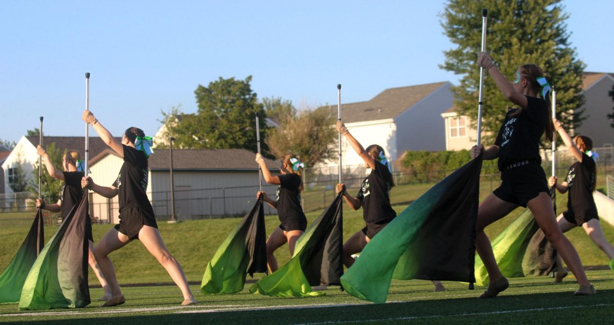 Several members of the GHS Color Guard look away as they lean with their flags on the football field. They performed their show for this year, "Gusto Italiano: A Taste of Italy," at their expo on August 6.