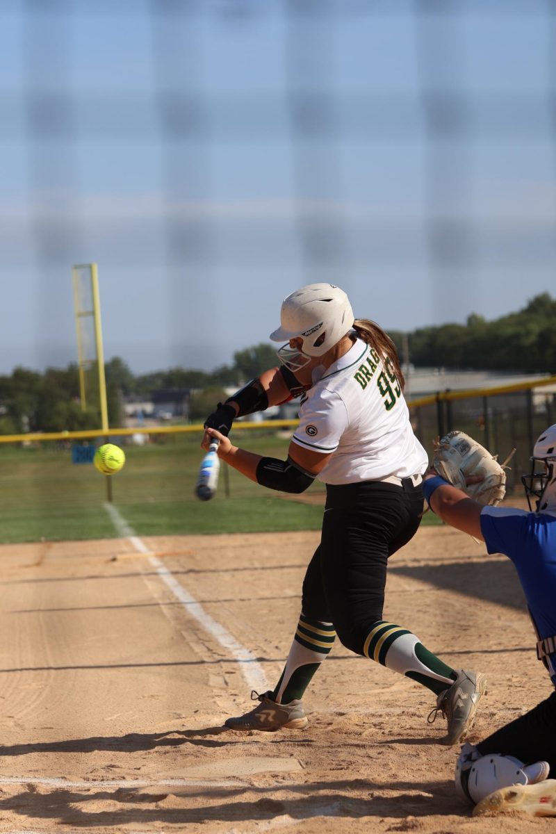 Senior Alexis Jensen, lead-off hitter, makes contact with the ball as the Dragons play Millard North. 
