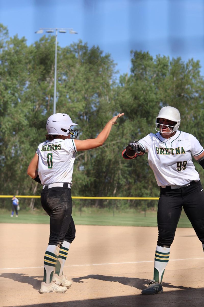 Senior Alexis Jensen and sophomore Maddie Kurrus high five after a successful play. 
