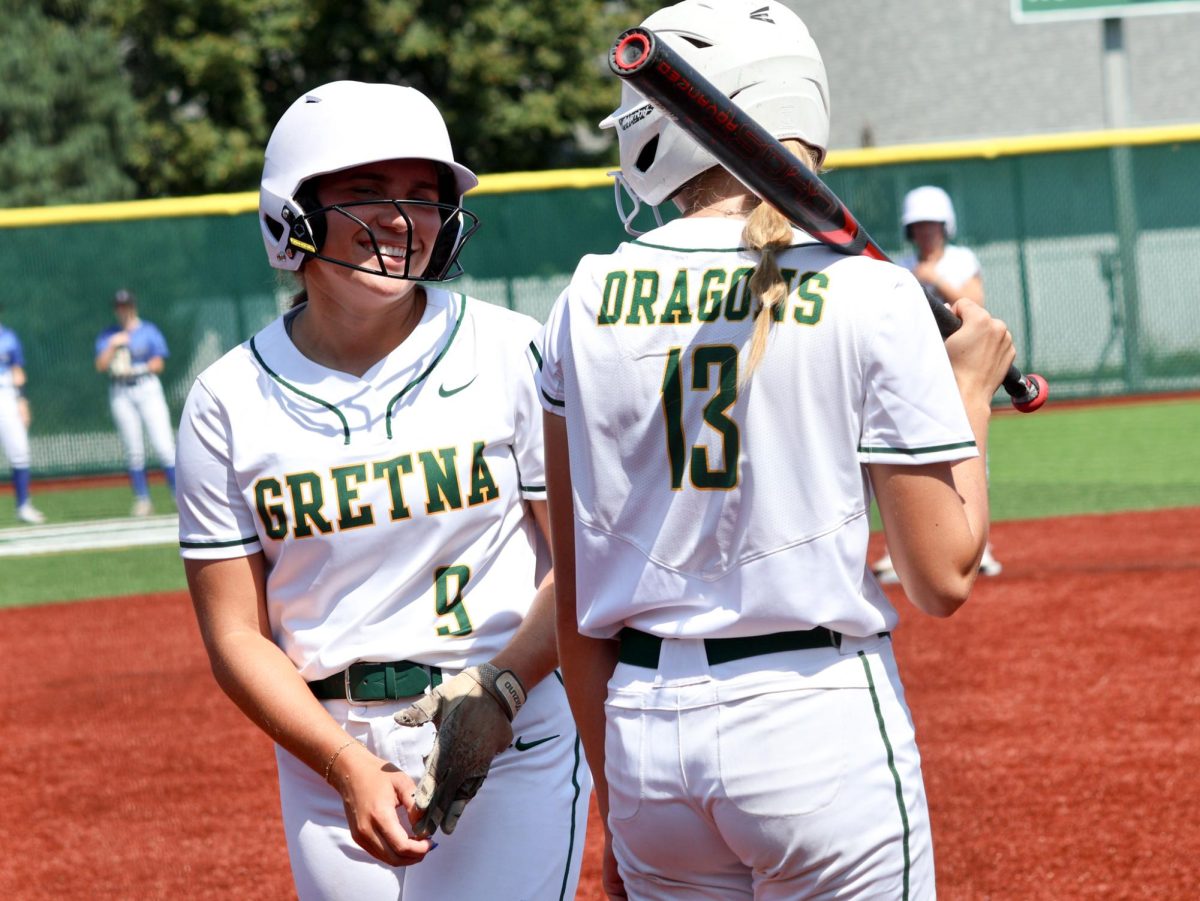 Brylee Rupiper (25) and Emerson Johnson (26) shares hitting details with Johnson before making her way up to bat at the Gretna vs. Omaha Marian scrimmage on Aug. 17. 