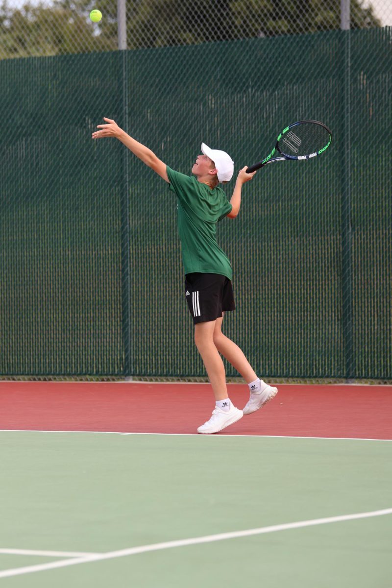 Freshman Brayden Stamm tosses the ball high into the air in preparation to hit his first serve. 