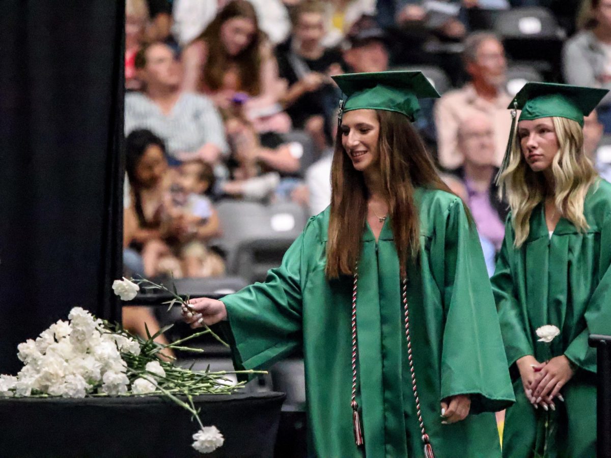 Graduated senior, Taylor Eurek (24), places a white flower in memory of Seth Feyerherm (24) who passed away in a car accident in December of 2023 after graduating at semester.