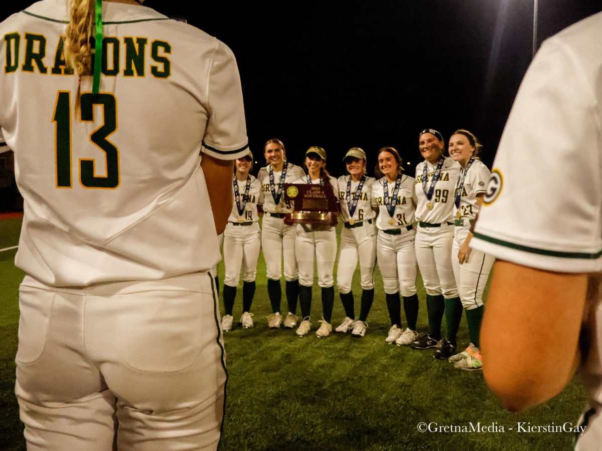 Junior Emerson Johnson snaps a picture of the team's seniors with their State Championship trophy.