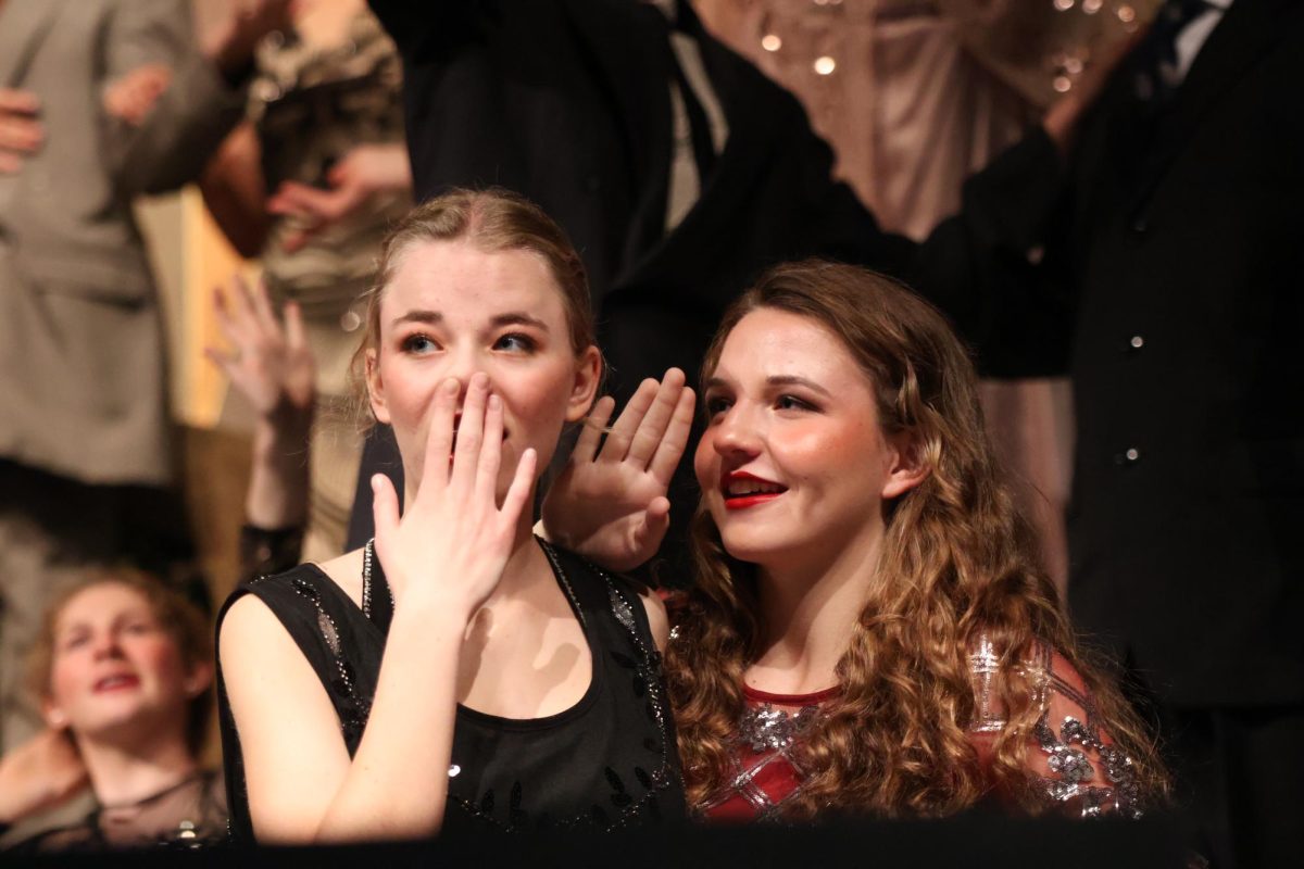 Sophomores Beth and Bri Wegner whisper quietly to each other while watching the scene unfold. 