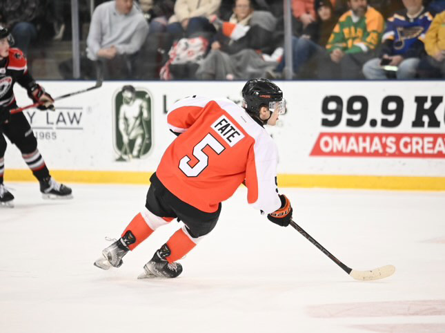 Fate skates around the rink alongside teammates and opponents as the game's spectators watch the match closely.