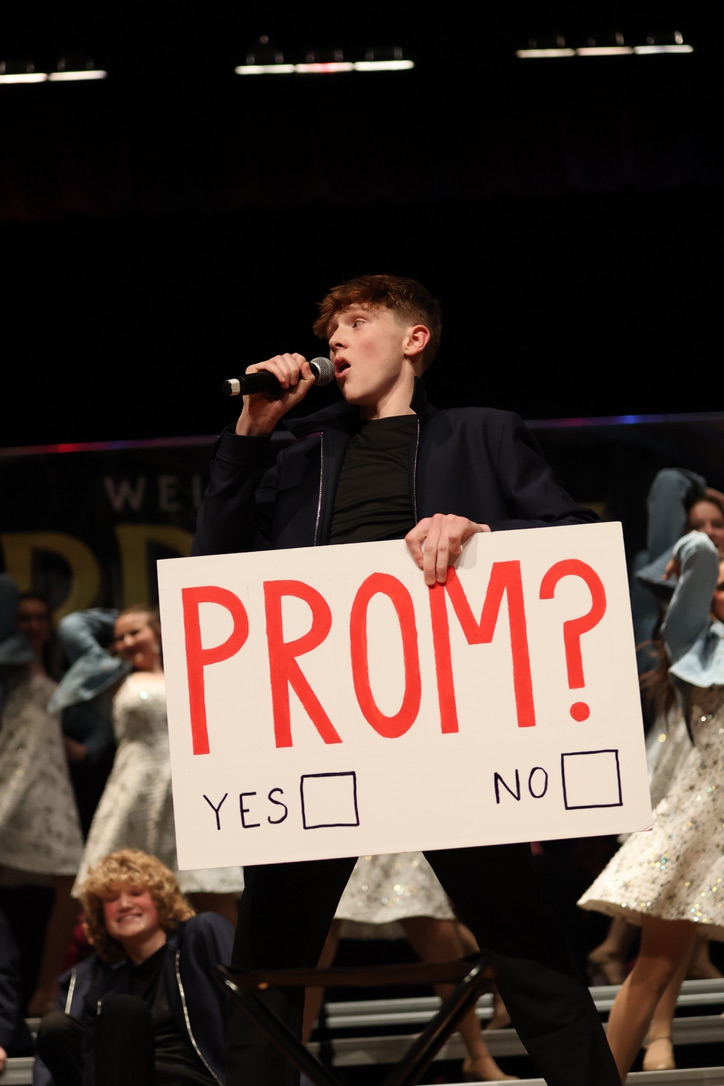 Freshman Ryan Sims presents a Prom sign to the audience.