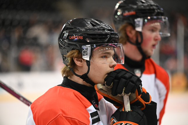 Suited up and stick in hand, Senior Mario Fate looks across the ice beside his Omaha Lancer's teammate.