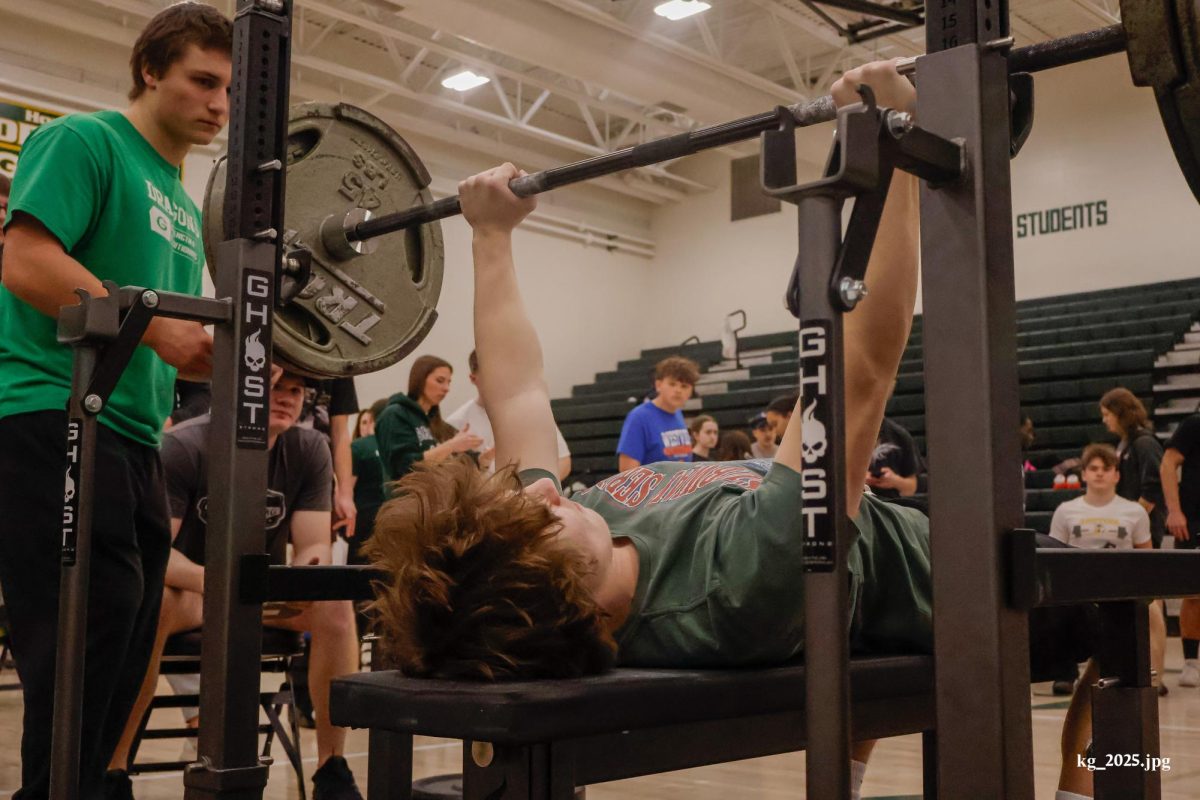 Sophomore Elliot Willnerd makes a bench press attempt while being spotted junior captain Alex Gibbons during Gretna's powerlifting meet on Feb. 8.