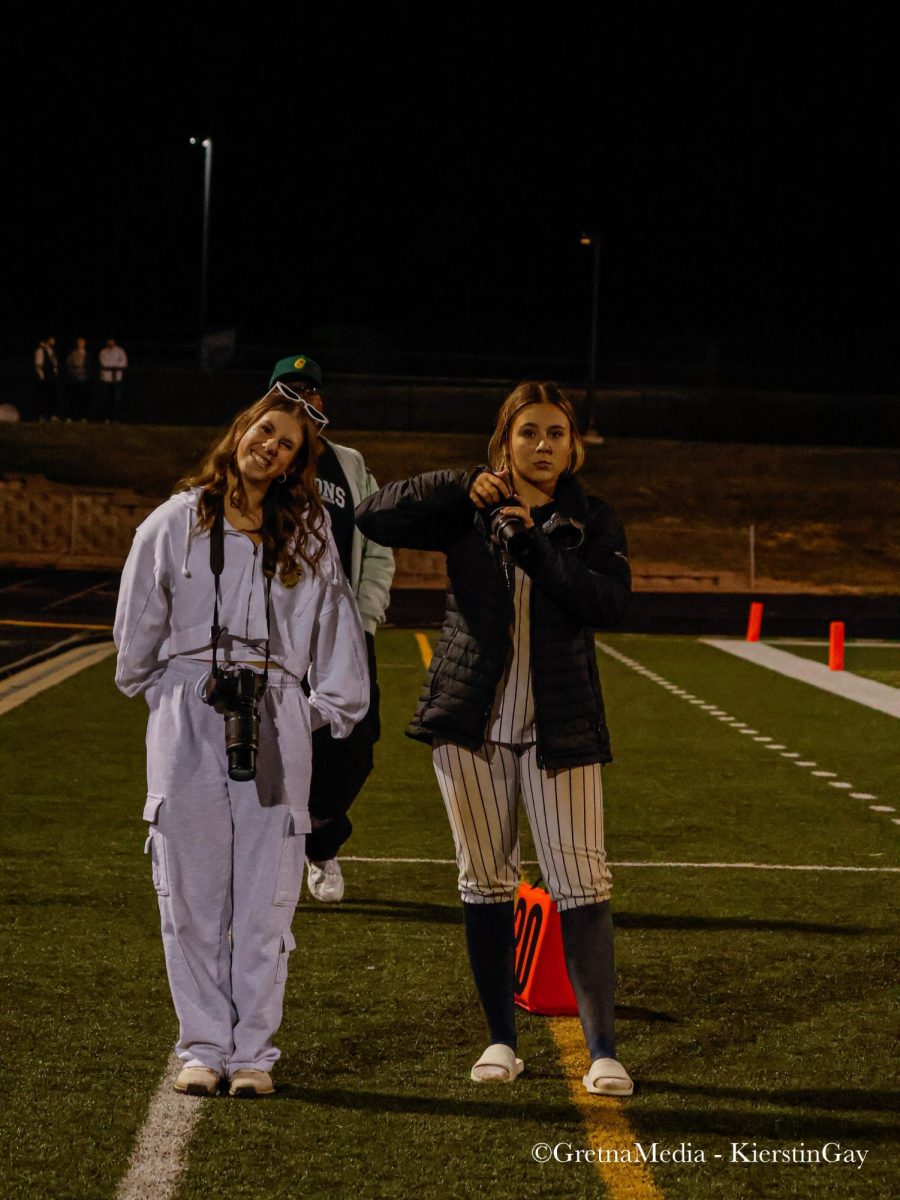 Freshmen Claire Palser and Callie McGee pose together while taking pictures at a Gretna football game at the GHS field.
