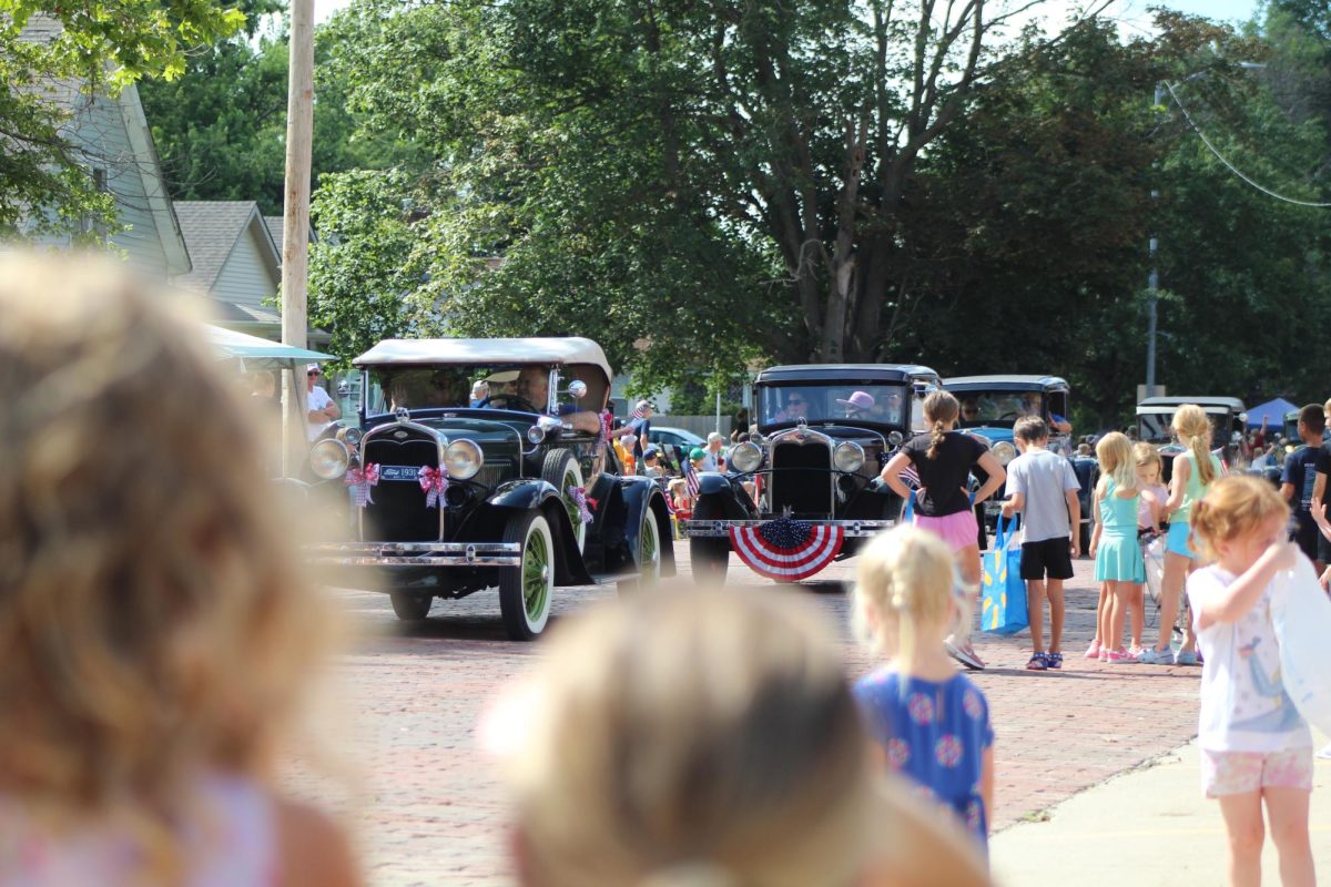 Gretna residents drive their decorated antique cars down Mckenna Avenue as children and community members watch on during the Grand Parade.