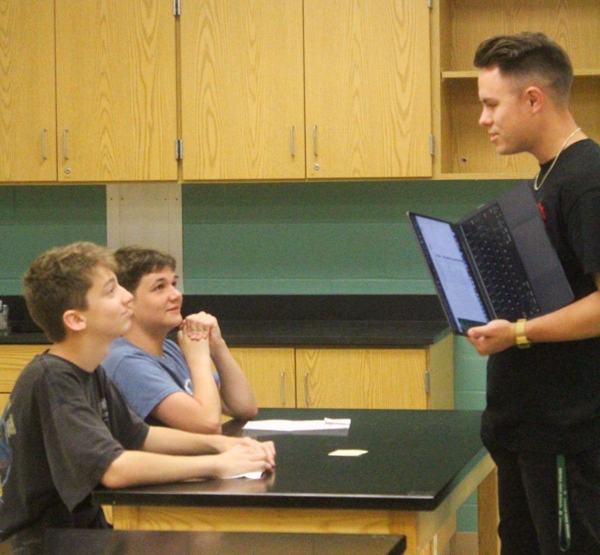 Choir teacher Dakota Mathews talks with two freshmen, Owen Rist and Zander Cox, in his study hall.
