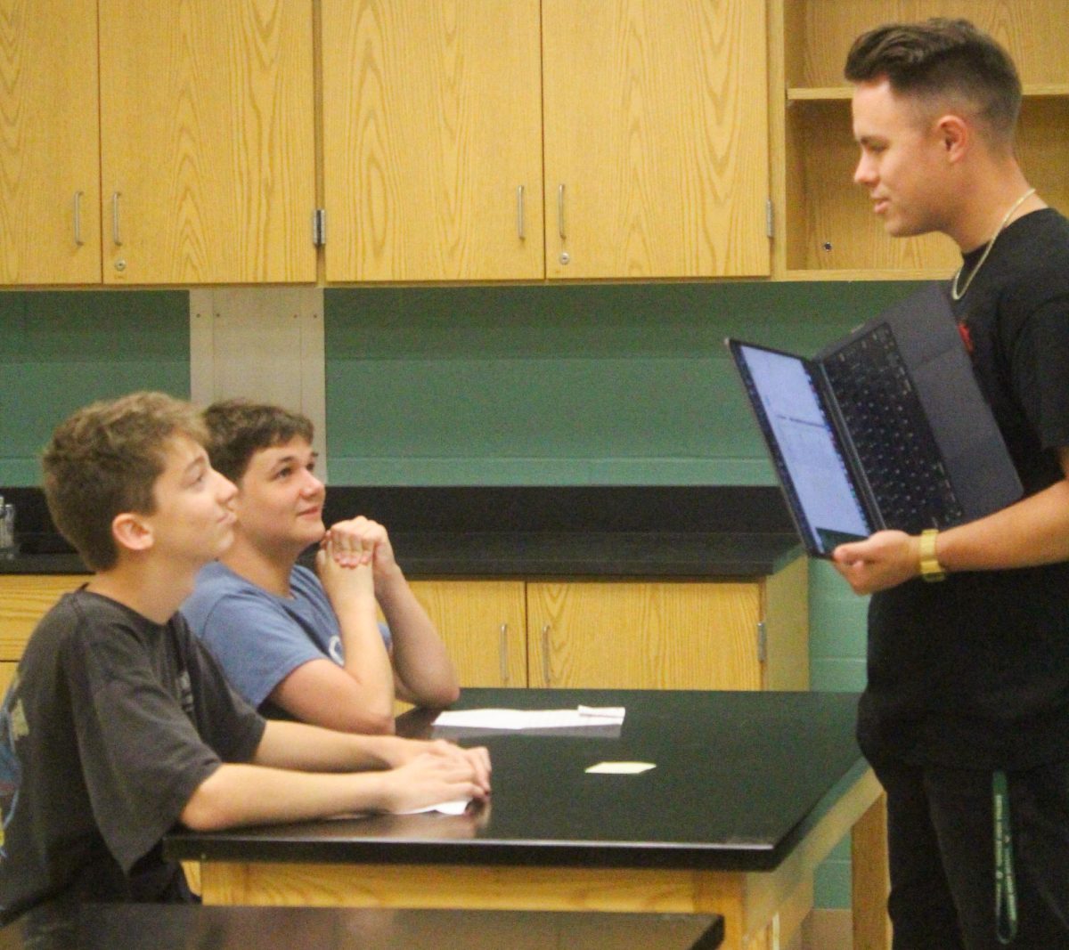 Choir teacher Dakota Mathew talks with two freshmen, Owen Rist and Zander Cox, in his study hall.