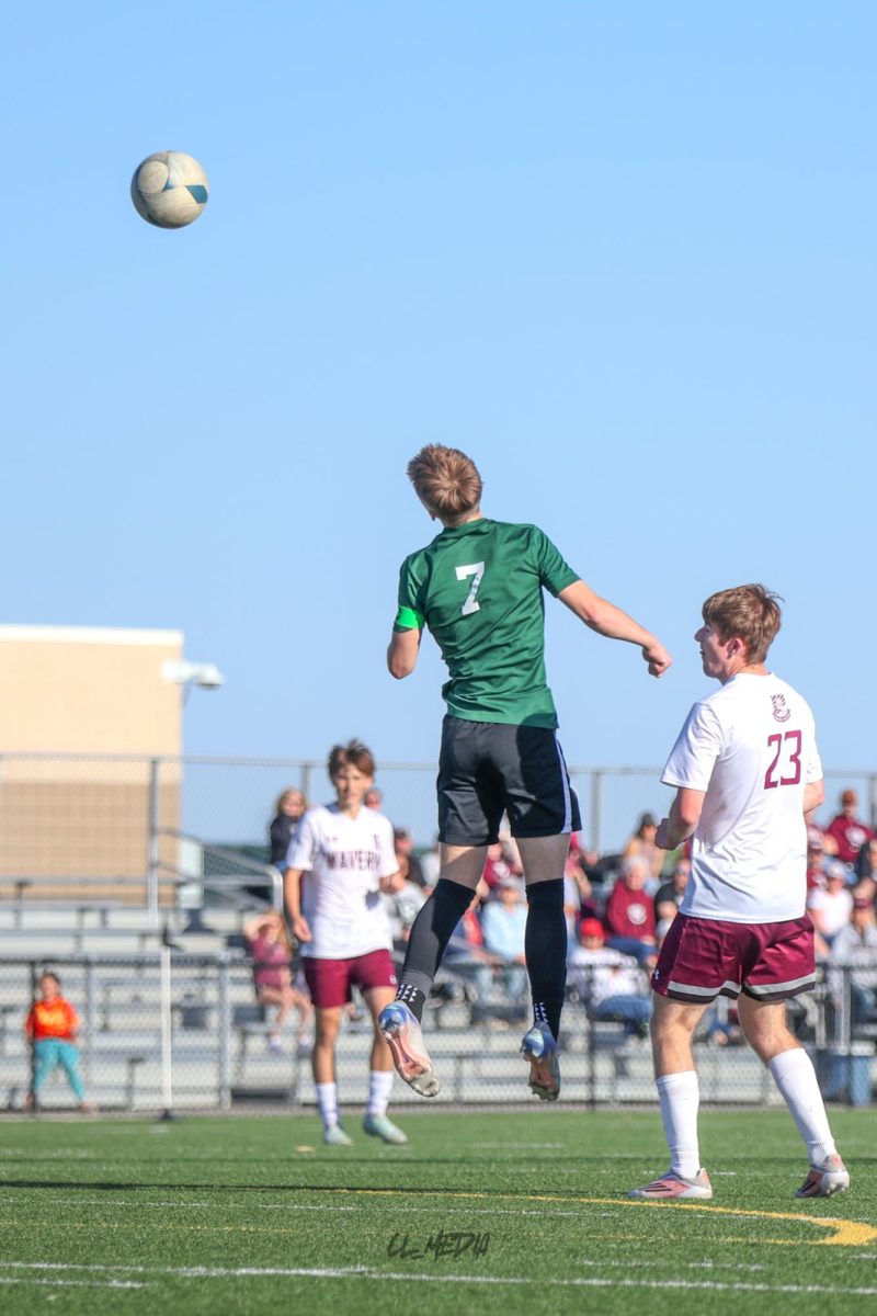 Senior Elijah Fulton leaps into the air heads the ball toward the goal during the District final on May 7.